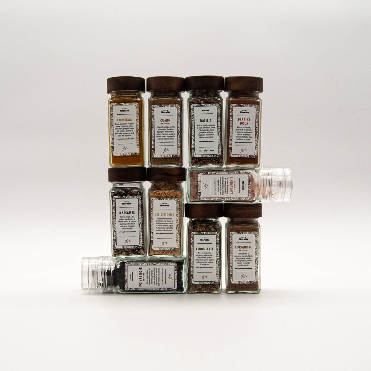 Fioles et moulins du coffret Les 10 Essentielles Épices Moralès empilés sur fond blanc.