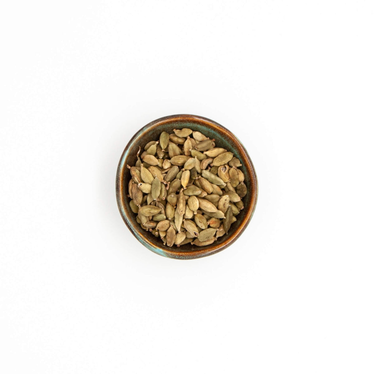 Bol de cardamome verte en graine Épices Moralès vu du dessus, gousses vertes entières pour thés et currys.