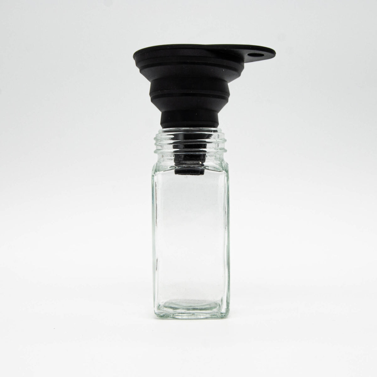 Entonnoir pliable Épices Moralès posé sur une fiole en verre vide, prêt à recevoir une recharge d'épices.