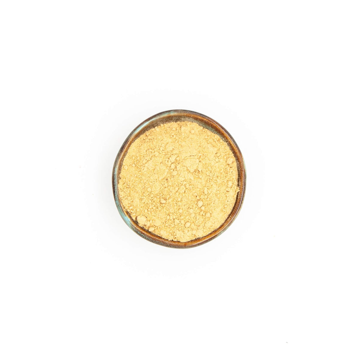 Bol de gingembre en poudre Épices Moralès vu du dessus, poudre jaune pâle pour biscuits, currys et boissons chaudes.