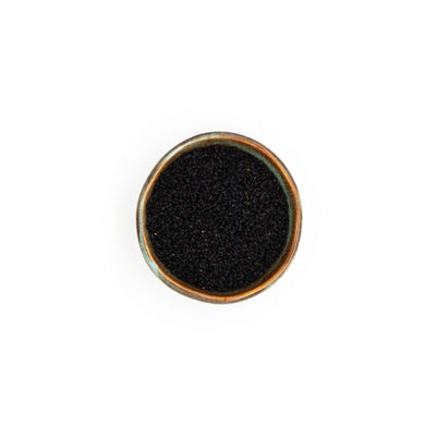 Bol de graines de nigelle Épices Moralès vu du dessus, graines noires anguleuses pour pains, naans et fromages.